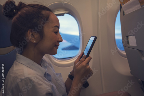 Asian woman a happy use of mobile phone inside airplane
