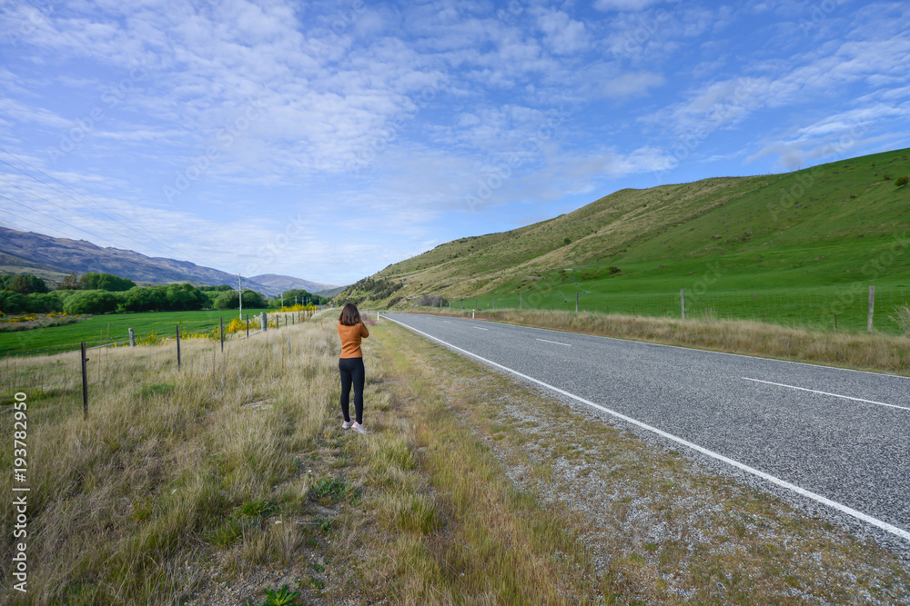 Woman photographer is take a photo at the highway roan in New Zealand