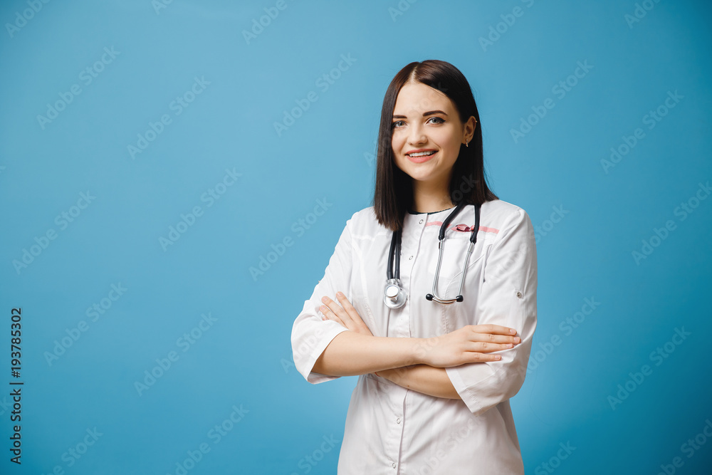 Portrait of female student doctor in white lab coat on blue background, on neck of stethoscope. Concept nurse