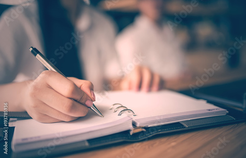 Close up of woman hand holding pen and writing on notebook,retre color design