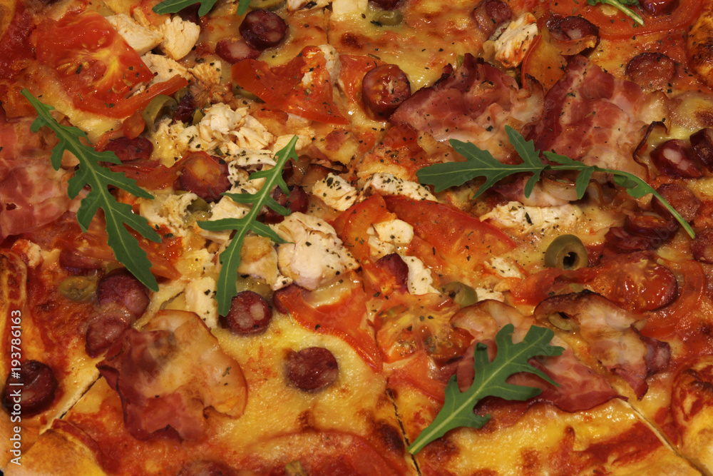 Pizza with bacon, sausages, ham, tomato and olives. Sprinkle with arugula and served with tomato and cheese. Pizza Restaurant. Snack, dinner Pizza with bacon, sausages, ham, tomato and olives. Sprinkle with arugula and served with tomato and cheese. Pizza Restaurant. Snack, dinner