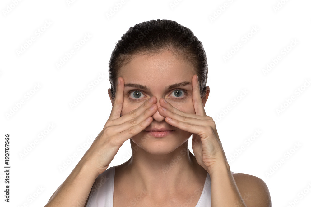 Massage, yoga, gymnastics or rejuvenating exercises for the face makes the girl own hands on a white background Massage, yoga, gymnastics or rejuvenating exercises for the face makes the girl own hands on a white background