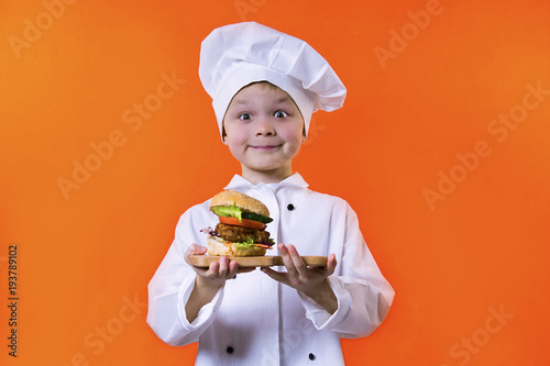 funny boy chef holding a sandwich on a board on a bright orange background