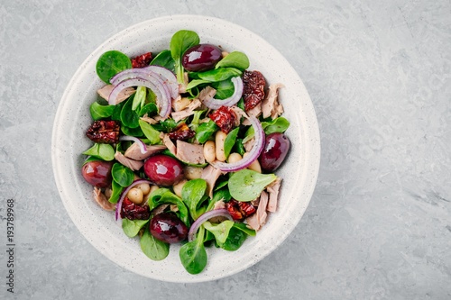 salad with white beans, tuna, olives, red onions and dried tomatoes with green lettuce leaves