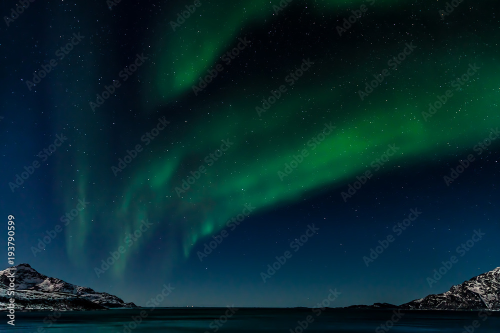 The northern lights over the mountains and the ocean in Grotfjord, Northern Norway