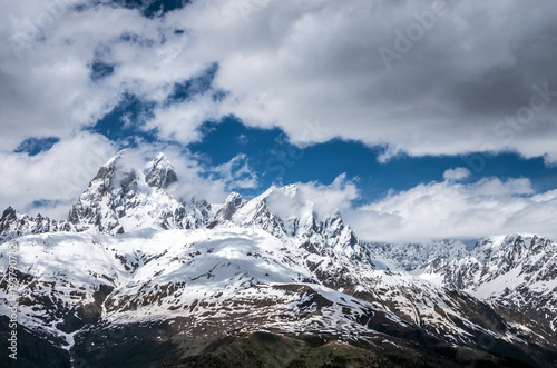 Blue sky with clouds over the snow-capped mountain peaks.