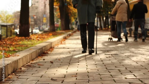 Old, person's city life. Senior lady, walk, in autumn park, limping with stick
