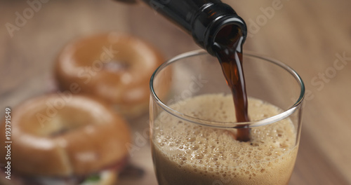 Canvas Print stout beer poring into glass with bagels on background
