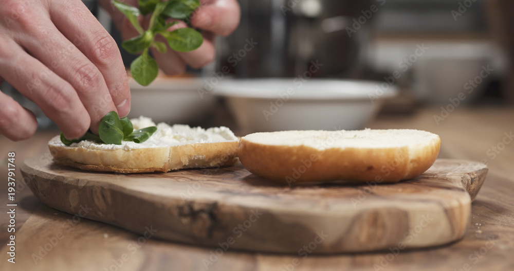 Man hands making bagel sandwich on wood board Man hands making bagel sandwich on wood board