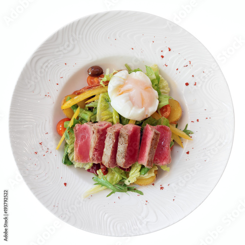 Nicoise salad of rare fried tuna, potato, salad mix and poached egg, white background