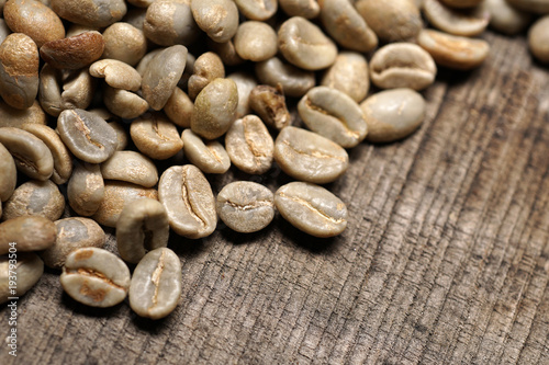 Unroasted  green coffee beans on wooden background - Extreme closeup