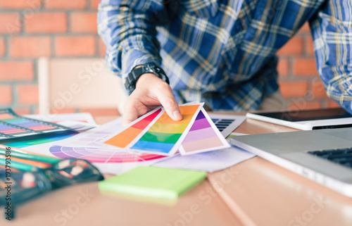 Designer choosing colors for doing graphic on laptop.
