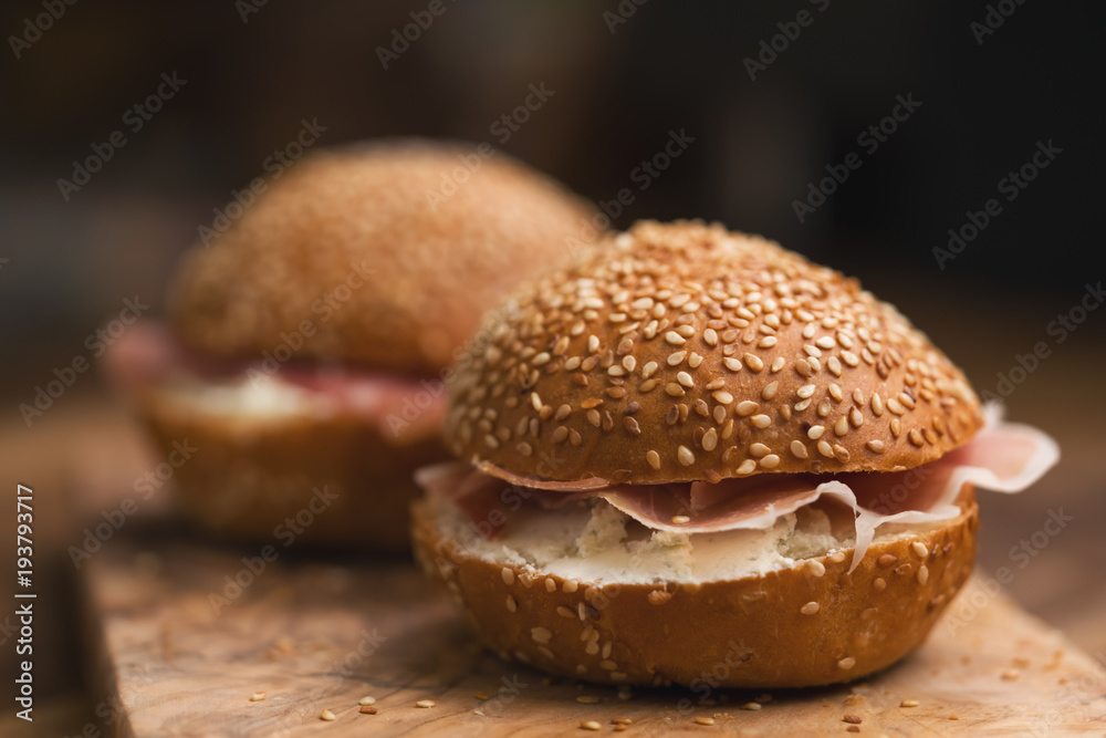 prosciutto and cream cheese in a sesame buns on wood board