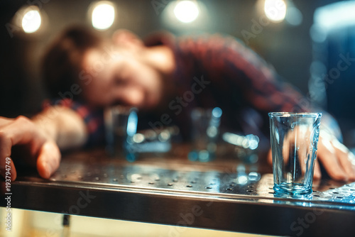 Drunk man sleeps at bar counter, alcohol addiction photo