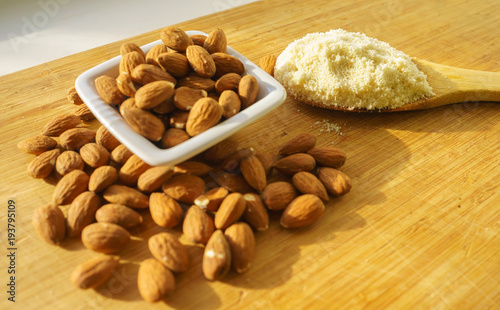 Almond flour in a wooden spoon on a background of nuts almonds.