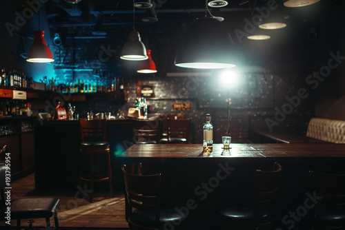 Fototapeta Pub, bottle of alcohol and glass on bar counter