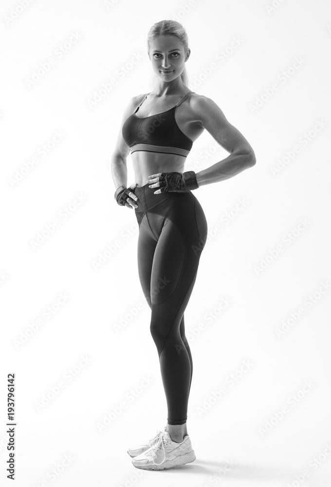 Full length portrait of fitness woman standing with her arms on hips Female model in sportswear over white background Full length portrait of fitness woman standing with her arms on hips Female model in sportswear over white background