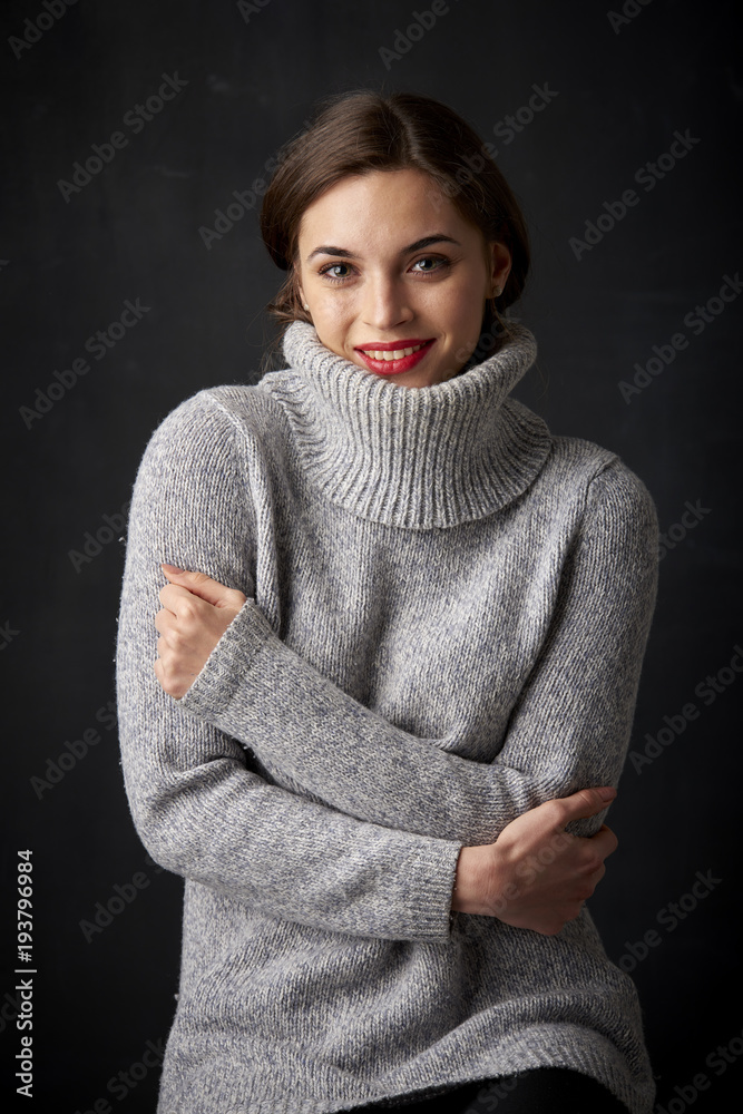 Portrait of beautiful young woman looking at camera and smiling while posing at dark background. Portrait of beautiful young woman looking at camera and smiling while posing at dark background.