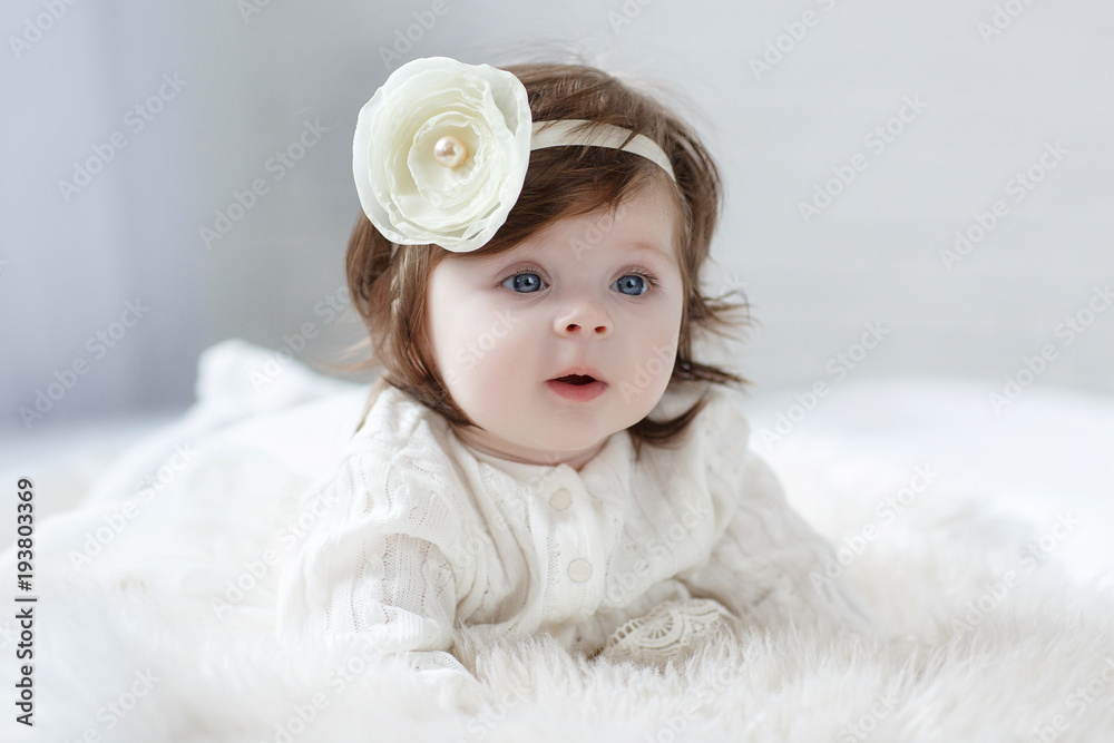 Close-up of a six, seven months old baby girl with blue eyes. Newborn child, little adorable smiling and attentive girl looking surprised at the camera. Family, childhood concept. Christmas Eve