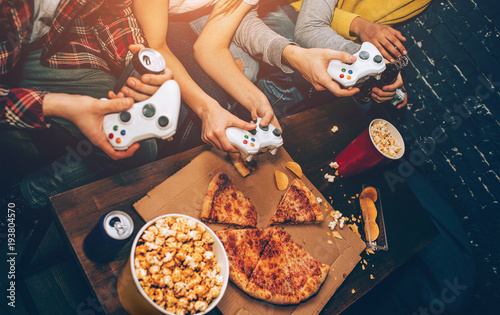 Food and drinks on table and four wireless gamepads