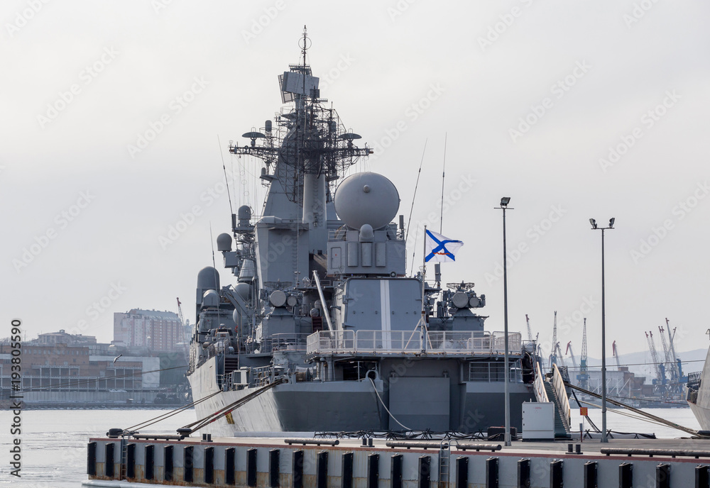 Modern Russian military cruiser battleship on the pierce. Russian Navy Ensign on the ship board. Russia, Vladivostok. Modern Russian military cruiser battleship on the pierce. Russian Navy Ensign on the ship board. Russia, Vladivostok.
