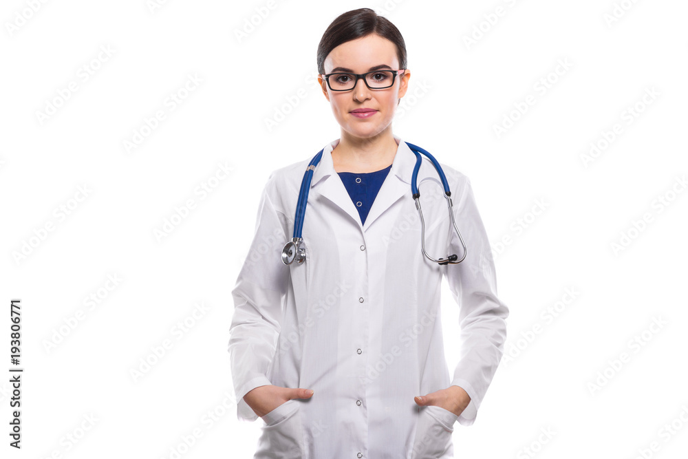 Young woman doctor with stethoscope holding her hands in pockets in white uniform on white background Young woman doctor with stethoscope holding her hands in pockets in white uniform on white background