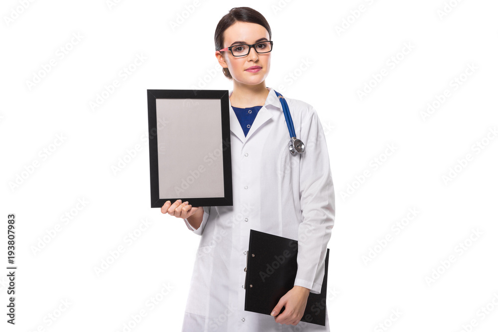 Successful young woman doctor with stethoscope holding clipboard and frame in her hands in white uniform on white background Successful young woman doctor with stethoscope holding clipboard and frame in her hands in white uniform on white background