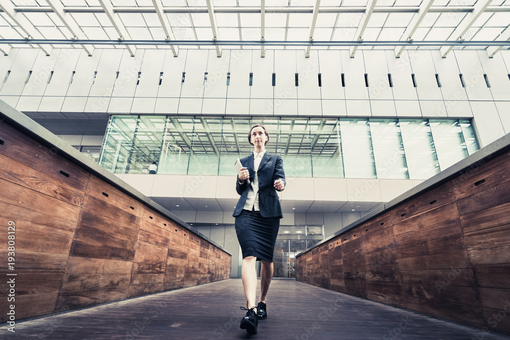 Obraz premium タブレットPCを手に歩く女性(ビジネスイメージ)