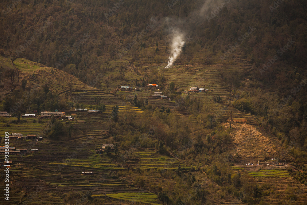 The mountain village in Nepal located on cascades and surrounded by greenery.