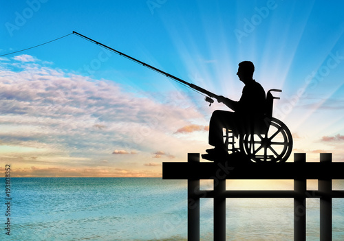 Obraz na plátne Silhouette of a disabled man in a wheelchair with a fishing rod in his hand fish