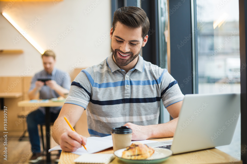 Joyful positive man taking notes Joyful positive man taking notes