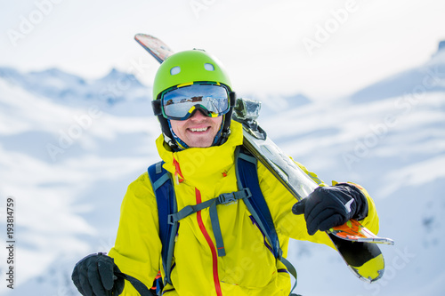 Photo of sporty man wearing helmet with ski on his shoulder