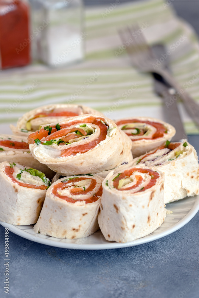 Rolls of thin pancakes with smoked salmon, cream cheese, chives and lettuce.