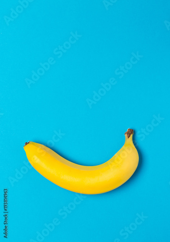 Single fresh, yellow, ripe banana on cyan