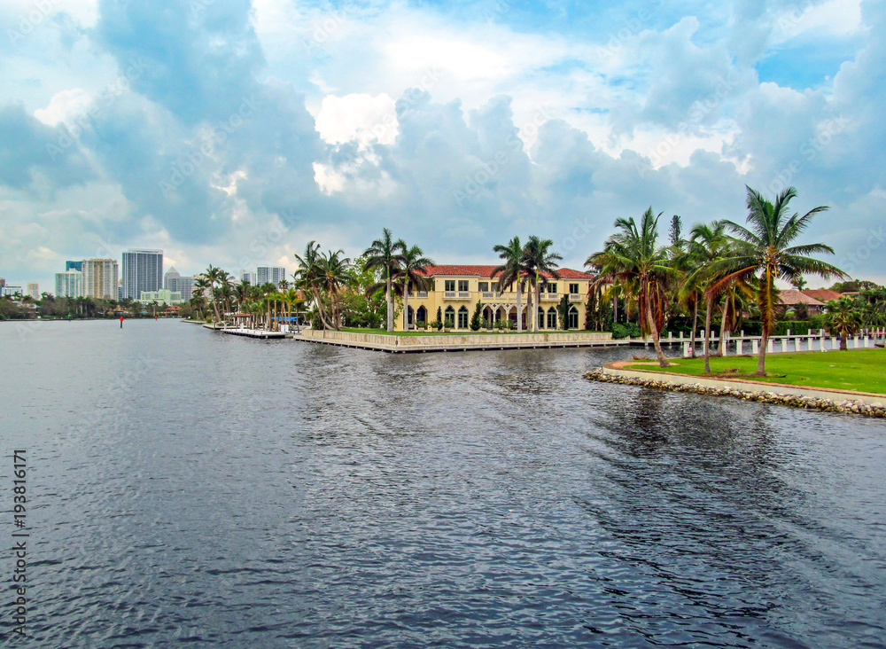 Canal of Fort Lauderdale, Florida, USA.
Panoramic view of downtown with luxurious estates, palm trees on the waterfront and boats on cloudy day. 