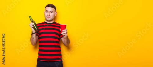 Handsome man in bright T-shirt with beer