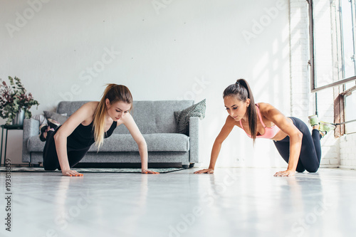 Two fit women doing push up exercise at home
