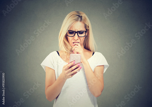 Confused young woman using phone