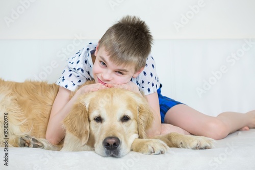 Happy Boy Playing With Golden Retriever Dog On Bed