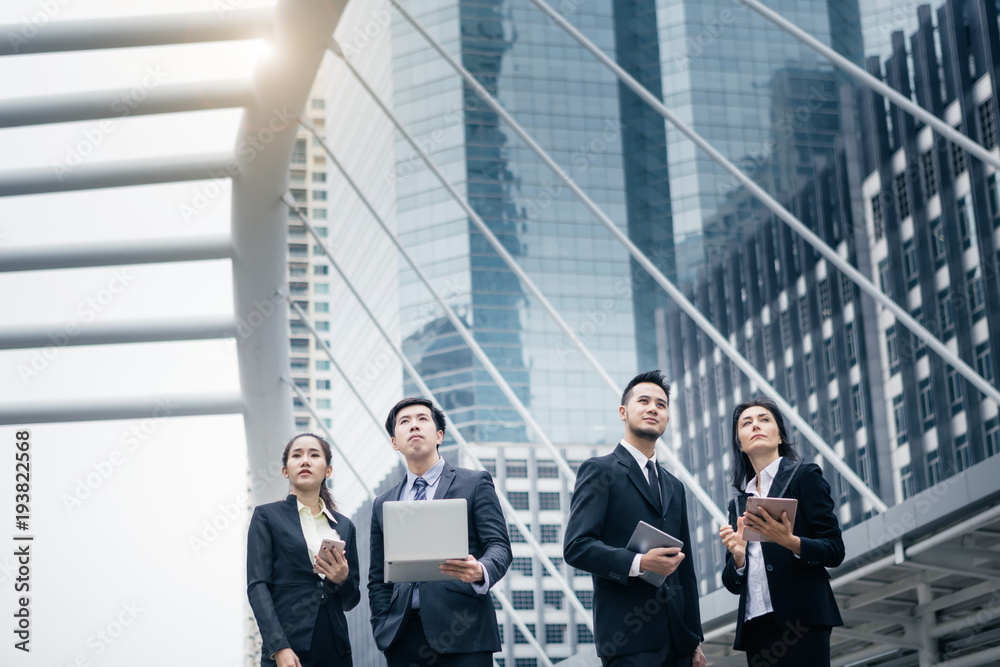 Group of business peoples standing outdoors with office building in the background, look to target at the sky