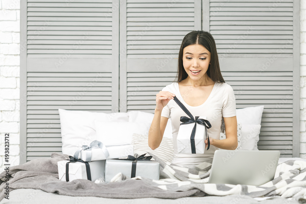 Smiling happy beautiful woman with gift boxes lying in bed. Morning surprise. Packing gifts. Online shopping. Smiling happy beautiful woman with gift boxes lying in bed. Morning surprise. Packing gifts. Online shopping.