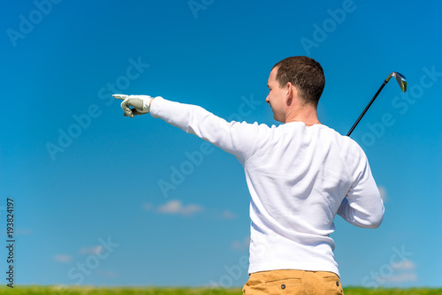 the golfer shows his hand the trajectory of the flight of his ball on the field
