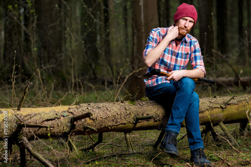 a lumberjack in the woods resting on a fallen tree