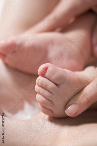 Baby feet in mother hands. Close up of little baby feet in hands of mother.Selective focus © arizanko