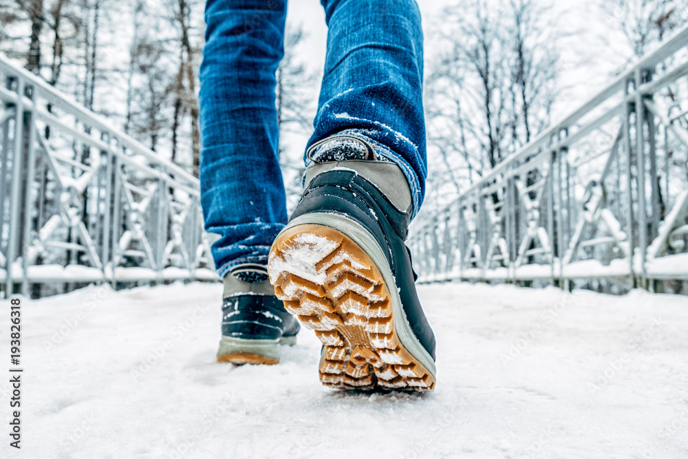 Fototapeta premium Man's legs in boots walking in the snow