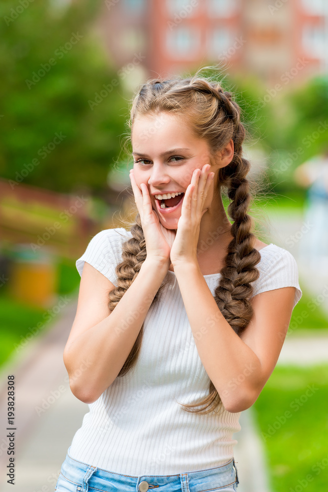 emotional joyful girl with two braids posing in summer park