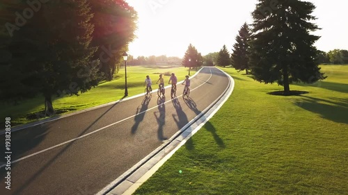 Cyclists on bikes outdoors, aerial view. Group of sporty friends riding a bikes on summer nature background, shooting from a height with a drone. Beautiful day for a ride. photo