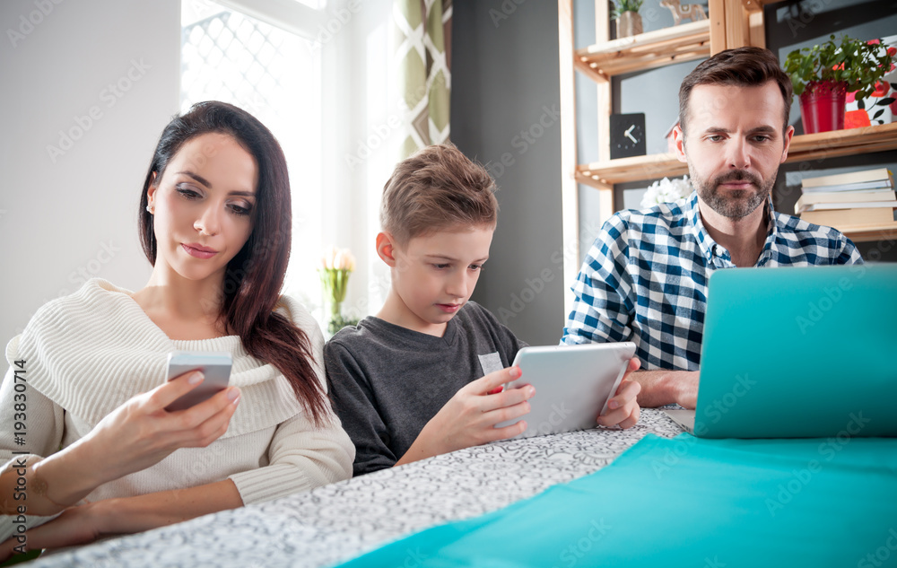 Family with laptop, tablet and smartphone, everyone using digital devices Family with laptop, tablet and smartphone, everyone using digital devices