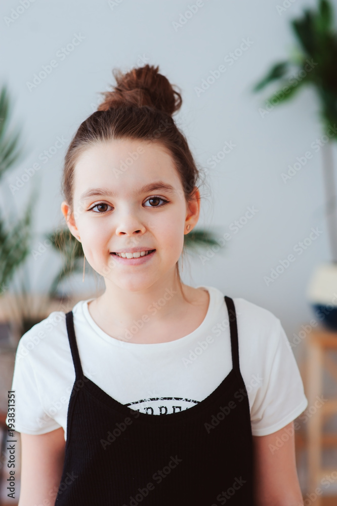 vertical indoor portrait of happy preteen girl posing in modern scandinavian interior, dressed in stylish black and white colors with tropical houseplants on background vertical indoor portrait of happy preteen girl posing in modern scandinavian interior, dressed in stylish black and white colors with tropical houseplants on background
