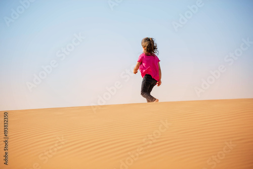 Cute little girl playing on the desert with sand